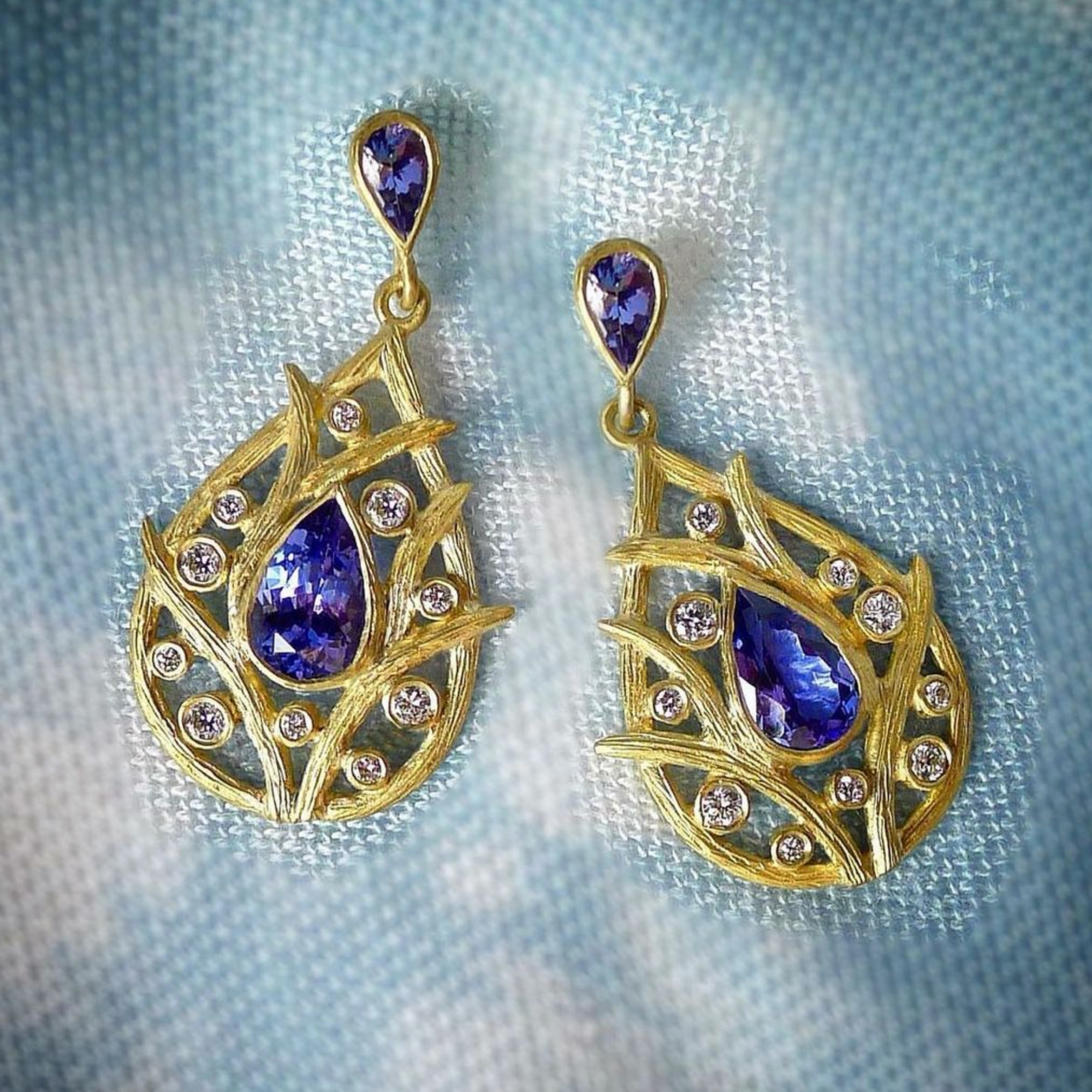 Vine Tanzanite Earrings by Laurie Kaiser available at Talisman Collection Fine Jewelers in El Dorado Hills, CA and online. Featuring pear-cut faceted tanzanites surrounded by 18k yellow gold vines and accented with 0.31 cts of white brilliant diamonds, these earrings are sure to make a statement. The secure post backs ensure comfortable and worry-free wear. You'll cherish these stunners for years to come.