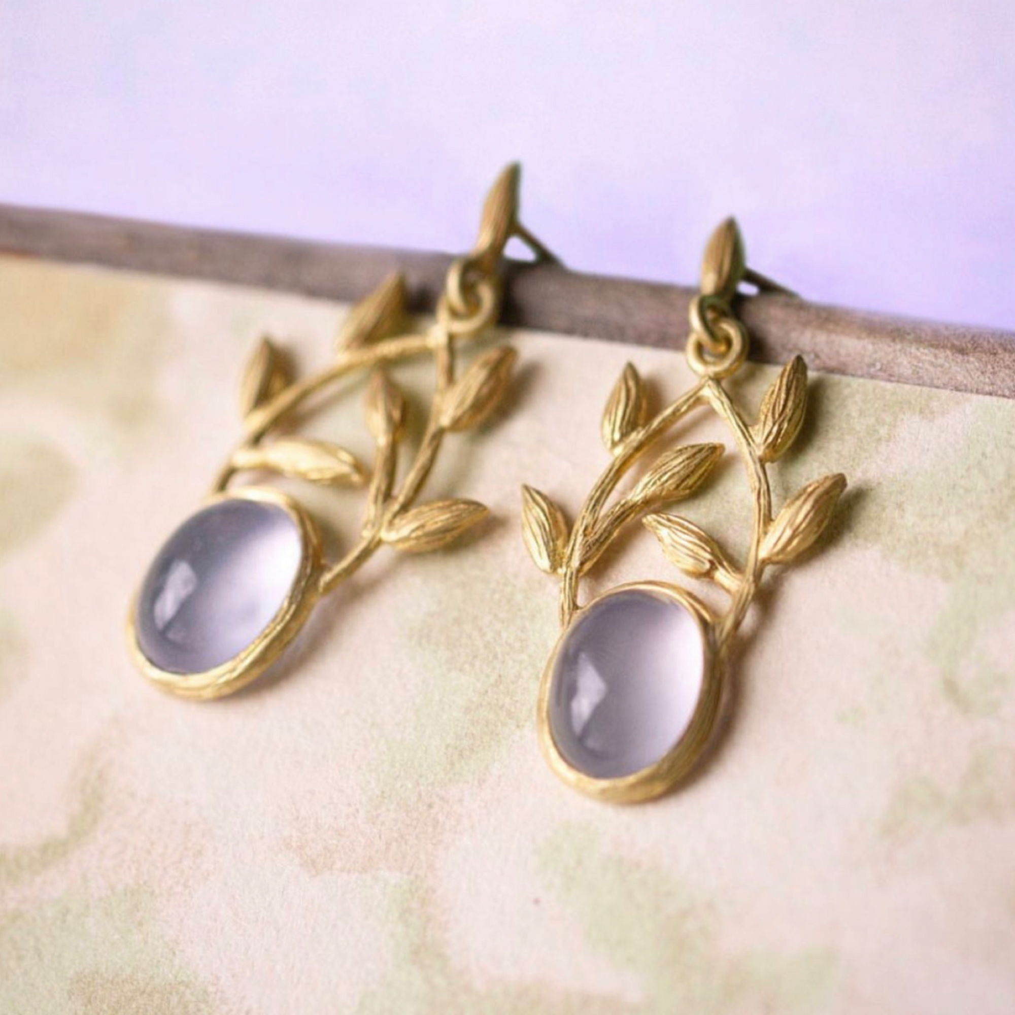  Chalcedony Leaf Crown Earrings by Laurie Kaiser available at Talisman Collection Fine Jewelers in El Dorado Hills, CA and online. The earrings feature lavender chalcedony cabochon ovals that dangle gracefully from 18k yellow gold vines. These lovey earrings secure with a comfortable post back closure.