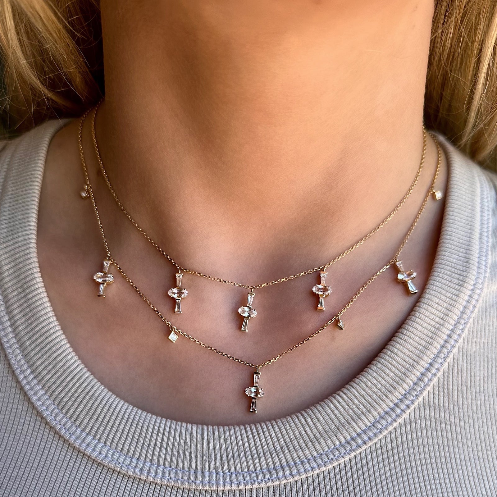 Diamond Sapphire Charm Necklace by Meredith Young, available at Talisman Collection Fine Jewelers in El Dorado Hills, CA and online. This necklace harmoniously merges the beauty of sapphires and diamonds. Adorning it are 1.5 cts of oval-cut sapphires, complemented by 0.58 cts of tapered diamonds, all dangling from a delicate 18k gold chain. The charms dance against your neck imbuing the piece with a touch of flirty style.