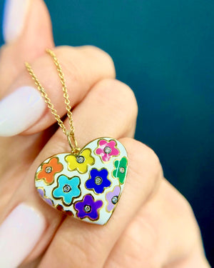 Enamel Flower Heart Pendant by Lord Jewelry available at Talisman Collection Fine Jewelers in El Dorado Hills, CA and online. This 18k gold, white enamel heart pendant is a vibrant piece with a retro, pop art feel. This pendant features charming colored flowers, each with a sparkling diamond center totaling .12 carats. It's a playful and unique accessory that adds a burst of color and whimsy; perfect for those who appreciate a touch of joyful individuality.