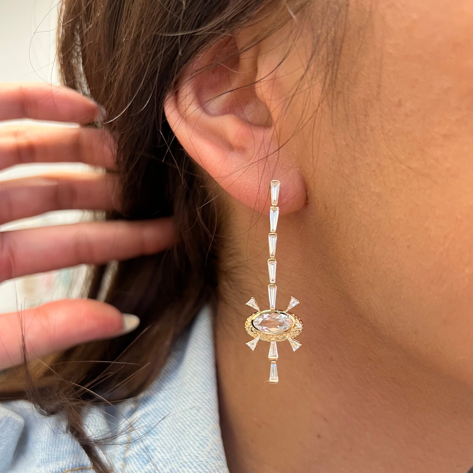 Supernova Hinged Earrings by Meredith Young available at Talisman Collection Fine Jewelers in El Dorado Hills, CA and online. These statement-making earrings are out of this world! Their celestial inspired design features 1.72 carats of tapered baguette diamonds arranged in a striking linear pattern, beautifully intersecting with 0.95 carats of oval-cut white sapphires surrounded by 18k gold. Finished with a classic post back, these earrings are as comfortable as they are spectacular.