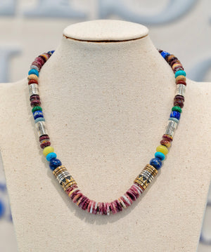 Tommy Singer Navajo Necklace available at Talisman Collection Fine Jewelers in El Dorado Hills, CA and online. Stats: Adorn yourself with a masterpiece of culture and tradition. This necklace features strikingly layered stones, handcrafted by the renowned Navajo artist, Tommy Singer. A vibrant blend of purple spiny oyster shell, lapis, turquoise, and pale serpentine, delicately accented by sterling silver and red brass, perfectly symbolizes the rich cultural heritage of the Southwest.