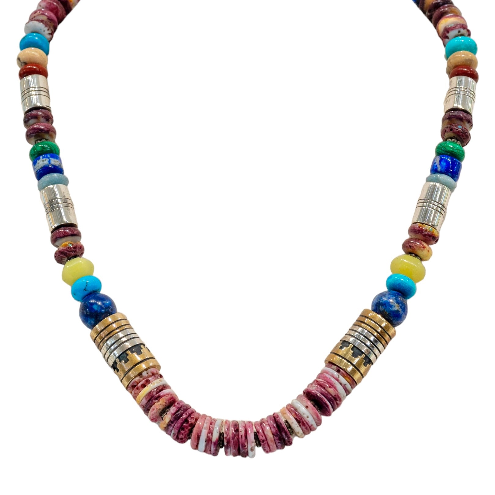 Tommy Singer Navajo Necklace available at Talisman Collection Fine Jewelers in El Dorado Hills, CA and online. Stats: Adorn yourself with a masterpiece of culture and tradition. This necklace features strikingly layered stones, handcrafted by the renowned Navajo artist, Tommy Singer. A vibrant blend of purple spiny oyster shell, lapis, turquoise, and pale serpentine, delicately accented by sterling silver and red brass, perfectly symbolizes the rich cultural heritage of the Southwest.
