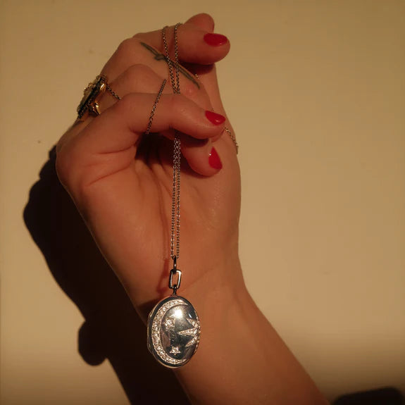 Galaxy Locket with White Sapphires by Monica Rich Kosann by Monica Rich Kosann available at Talisman Collection Fine Jewelers in El Dorado Hills, CA and online. Our Galaxy Locket captures the beauty of the cosmos with white sapphire accents forming a sun, moon, and stars. Designed to hold two images, this locket is finished with rhodium for lasting shine and tarnish protection. Measuring 1 1/16" tall and 13/16" wide, it’s strung on a 22" cable chain with an additional loop at 20" for adjustability. A perfec