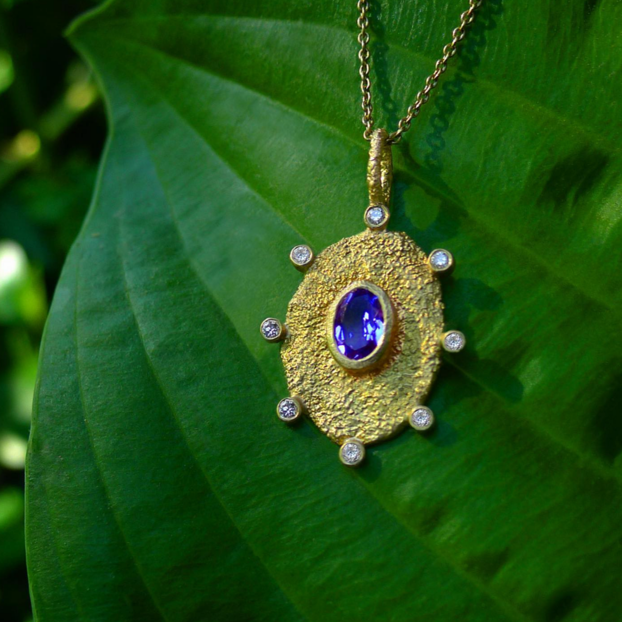 Rustic Tanzanite Necklace by Laurie Kaiser available at Talisman Collection Fine Jewelers in El Dorado Hills, CA and online.This pendant necklace features an oval cut tanzanite and 0.12 carats of brilliant white diamonds, all set in 18k gold. The organic shaped oval pendant hangs from a delicate 16" yellow gold chain. This necklace will add a touch of natural beauty to any outfit.
