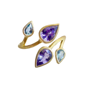Tanzanite Triple Vine Ring by Laurie Kaiser available at Talisman Collection Fine Jewelers in El Dorado Hills, CA and online. Features pear cut Tanzanite and Swiss blue topaz stones set on an 18k yellow gold band that delicately wraps around your finger. The vibrant colors of the stones create a enchanting effect, and the simplicity of the design adds to its timeless appeal. A must-have for anyone looking for a unique and elegant piece of jewelry!