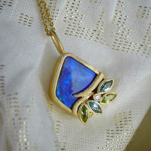 Petal & Vine Opal Necklace by Laurie Kaiser available at Talisman Collection Fine Jewelers in El Dorado Hills, CA and online. Featuring a mesmerizing Boulder opal surrounded by peridot, Swiss blue topaz, and white diamonds, this Petal & Vine necklace is a true work of art. Crafted from 18k yellow gold and complemented by an 18" chain, it exudes sophistication and luxury. Add this exquisite necklace to your jewelry collection for a touch of elegance that will never go out of style.