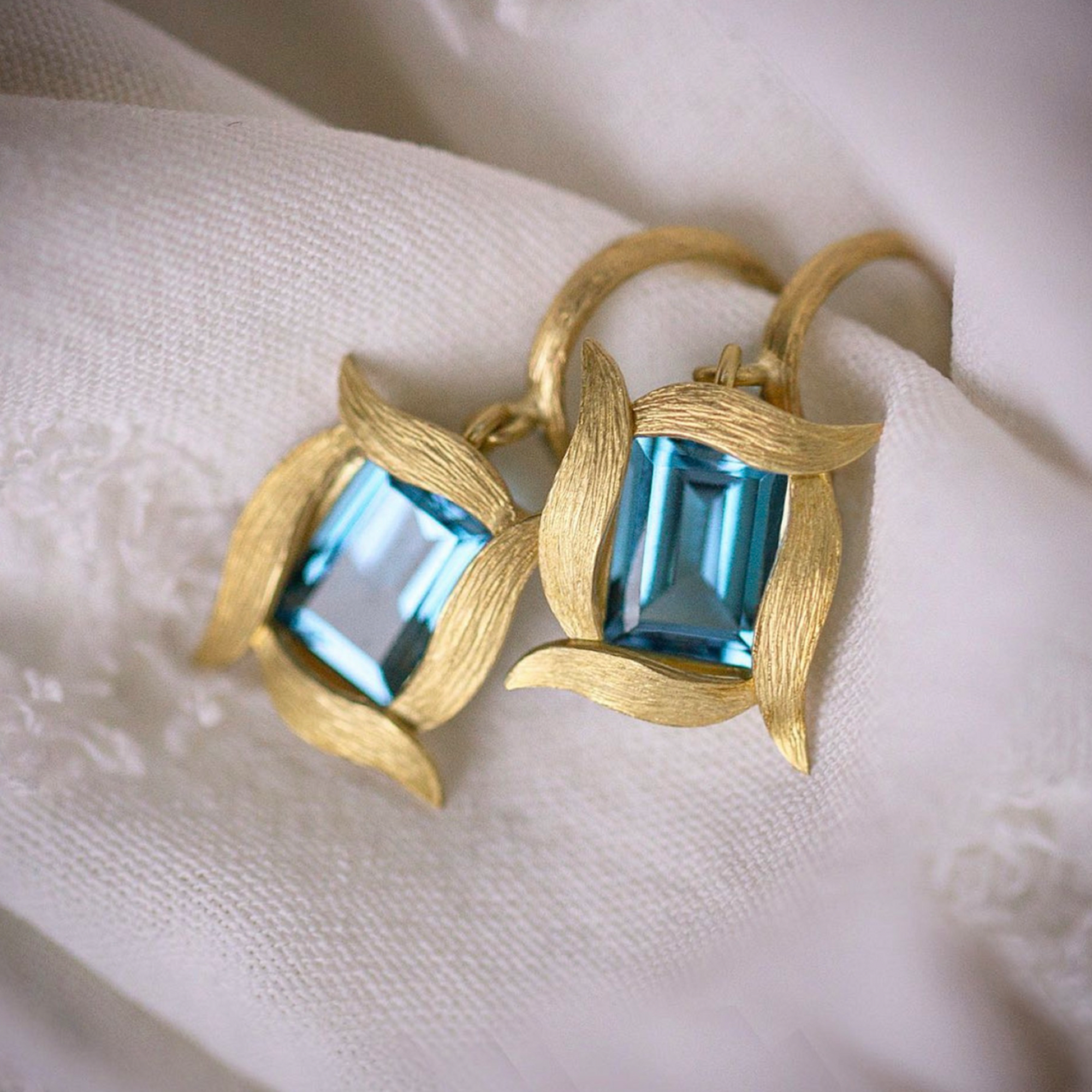 Blue Topaz Vine Hoop & Drop Earrings Laurie Kaiser available at Talisman Collection Fine Jewelers in El Dorado Hills, CA and online. Emerald cut London blue topaz stones framed by 18k yellow gold vines. The elegant and understated design adds a touch of sophistication to any look, while the small hoop makes them comfortable to wear all day.
